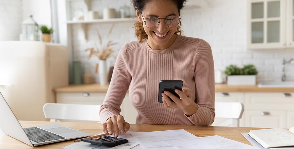 Person using their phone and a calculator to do finances.